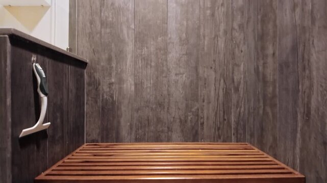 close-up of a built-in wooden bench seat in a modern stone-textured shower