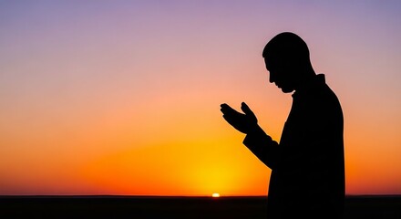 Fototapeta premium Silhouette of a man praying at sunset with open hands