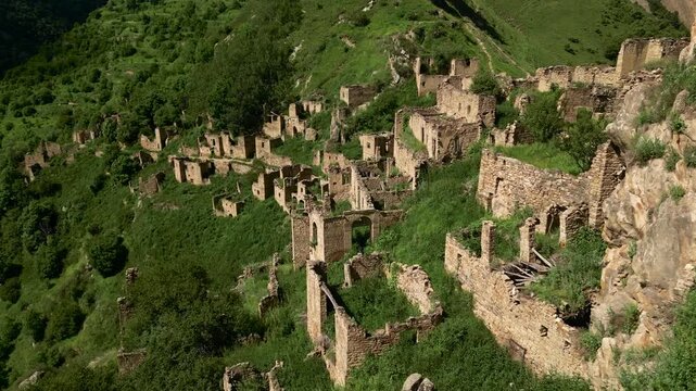 Drone aerial view of the abandoned mountain village of Gamsutl in Dagestan at sunrise with soft morning light and dramatic scenery.