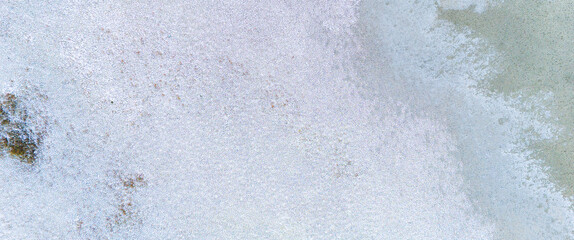 Detailed aerial texture of a winter landscape with light grey mud and white frost creating a soft and complex natural background from above © Buğra Kaan Ersoy