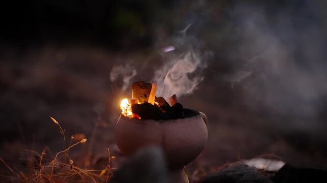 Hand adds ocote to sacred fire during Mayan ceremony in Guatemala