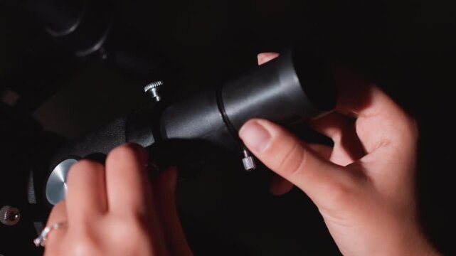 hands adjusting telescope eyepiece at night, closeup of fingers swapping lens and fine tuning focus, smartwatch on wrist, metal mount and tripod visible, low light atmosphere, hobbyist researcher
