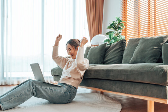 Funny euphoric young asian woman celebrating winning or getting ecommerce shopping offer on computer laptop. Excited happy girl winner looking at notebook celebrating success