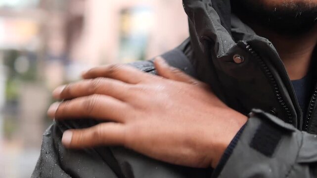 Close-up of Hand Wiping Water Off a Waterproof Jacket