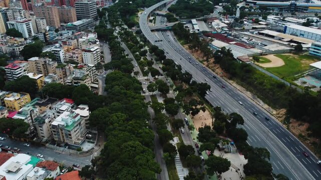 Vista de drone en autopista de caracas Venezuela sobre veh&iacute;culos en movimiento. Vegetaci&oacute;n en la ciudad entre edificios y el r&iacute;o guaire