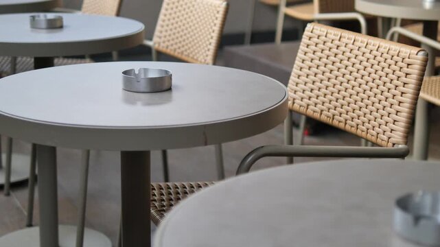 Outdoor cafe with empty tables and ashtrays around
