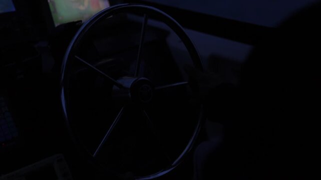 4K close-up of a fisherman's hands steering a fishing boat during departure in the dark early morning on Iriomote Island. Cinematic low light shot focusing on the helm and manual navigation.