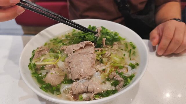 Fatty Pho Bo with rich bone broth is very filling meal. Hot Fatty Pho Bo has sliced oily beef and rice noodles. Traditional Fatty Pho Bo is nutritious asian soup for lunch in local restaurant.