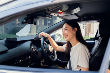 Naklejka premium Smiling Asian business woman is driving a car on the road