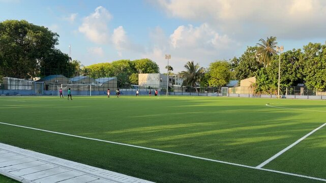 Football pitch on local island in Maldives with players training on artificial turf