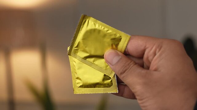 Showing packets of condoms held on finger.