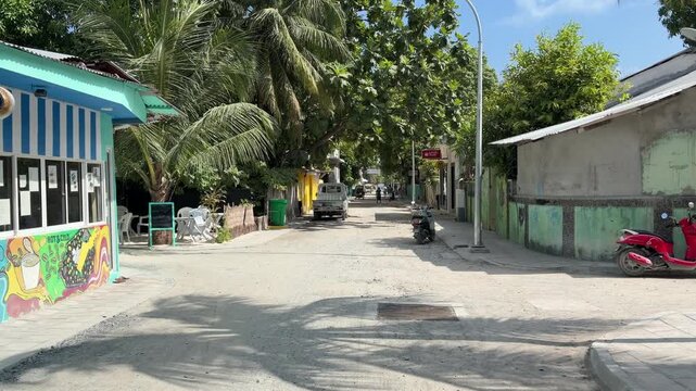 Quiet sandy street in Ukulhas Maldives lined with palm trees and island houses
