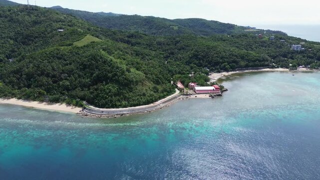 Aerial drone of Romblon coastline with crystal-clear turquoise water, green forested hills, and blue sky, showcasing tropical scenery, scenic landscapes, and exotic island views in the Philippines.