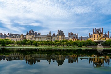 Obraz premium Discover the stunning Chateau de Fontainebleau, a historic palace set by a serene pond. This architectural gem showcases France s rich heritage and draws visitors from around the world.