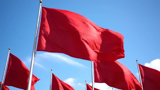 Bright red flags fluttering in the wind against a clear, blue sky