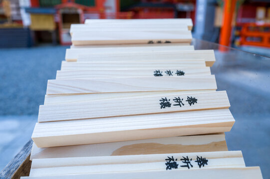 Neatly stacked wooden prayer sticks with Japanese calligraphy are displayed at Kumano Nachi Taisha in Wakayama, Japan. Soft daylight highlights the smooth grain and natural texture of the wood against
