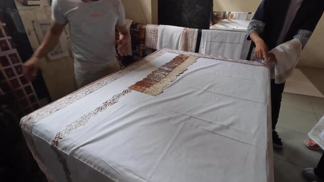 Hand printing batik with traditional wax stamps dipped in hot wax on white Ccotton fabric, Indonesian textile craft process in 4K