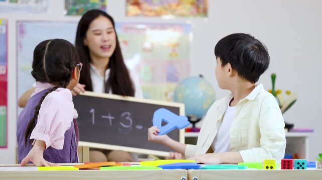 Asian Elementary Students Learning Math with Teacher in Bright Classroom