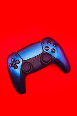 A gamepad for consoles on a red background, gaming addiction, gaming ban for teenagers, gaming controls for parents, for banners and advertising. High quality © Karen Vardanian