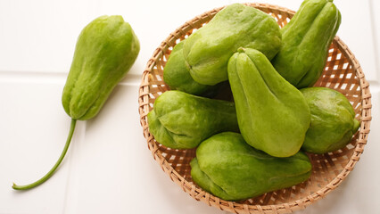 A pile of green chayote squash on bamboo plate