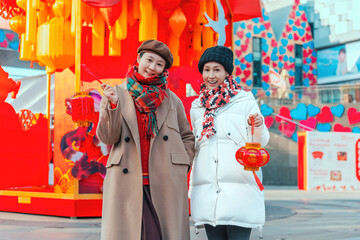 Two Women in Festive Attire Holding Red Lanterns