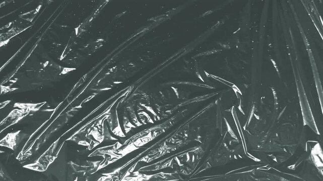 Abstract textured gray plastic wrap surface reflecting light and shadow