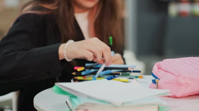 asian student selecting colorful pens at cafe table, pink pouch and notebook in frame, hands choosing markers for colorcoding notes, energetic focused vibe with warm bokeh background and casual study