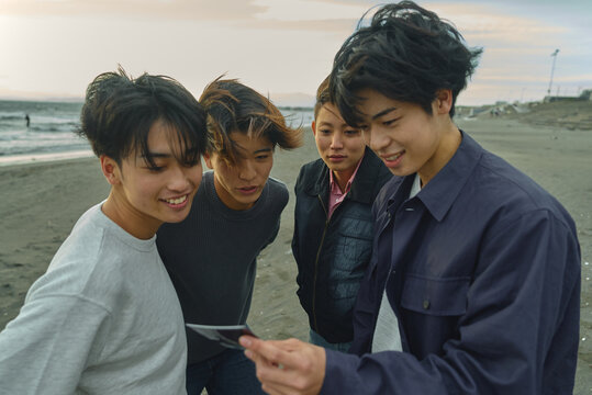 撮影した写真を見る若い男性4人