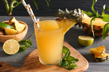 Fototapeta premium Glass of fresh pineapple juice with mint leaves and lime on dark wooden background