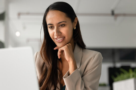 Close-up of young 30s professional woman working on laptop, review project updates, using new program or digital tools, reading work-related e-mail or article at workplace. Innovative business tech