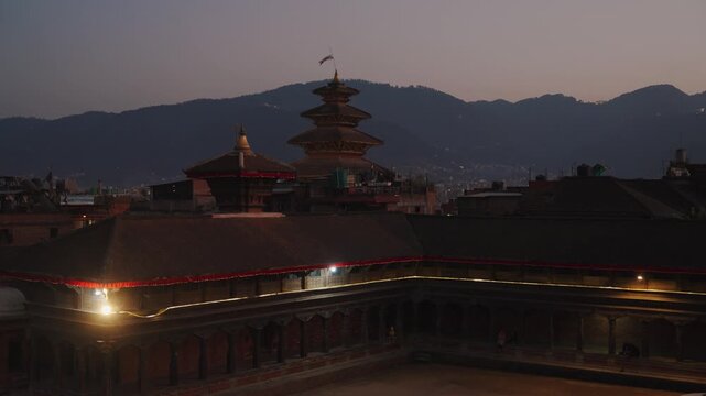 Evening scene at Bhaktapur Durbar Square with illuminated pagoda roofs and fading blue sky
