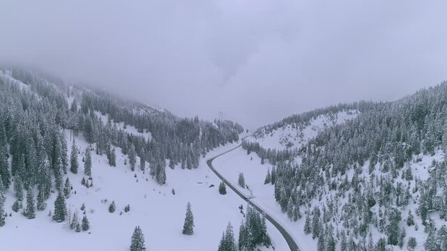 Forward moving drone shot flying along a snowy mountain road during winter whiteout near Col du Pillon Les Diablerets Gstaad showing alpine landscape cold weather and dramatic Swiss Alps scenery