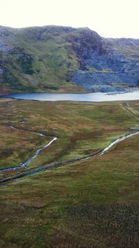 Abandoned slate quarry valley with calm lake and weaving small rivers in North Wales landscape. Ideal for travel vlogs and nature-themed Reels. Vertical video 9:16 format.