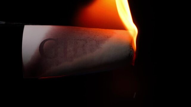 Burning sheet of paper with the word GIFTS, close-up on black background