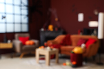 Naklejka premium Blurred view of living room decorated for Halloween with sofa, armchair and fireplace