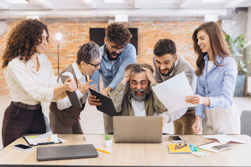 Stressed businessman receiving pressure from coworkers, feeling burnout and overwhelmed by a frantic workplace deadline
