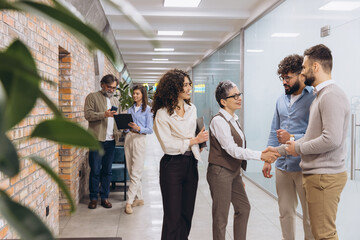 Business people meeting in office hallway, collaborating and shaking hands for partnership, startup...
