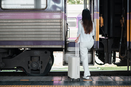 Woman in white outfit boarding a train with luggage, symbolizing travel and adventure.
