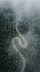Winding mountain road through misty forest landscape