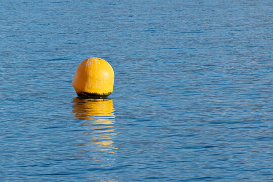Bou&eacute;e de signalisation jaune flottant sur une surface d'eau bleue calme