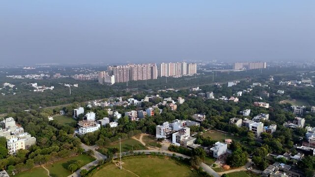Aerial video of Greater Noida showing scattered independent houses, lush urban forests, and a backdrop of modern high-rise apartments, highlighting the city&rsquo;s blend of greenery and rapid development