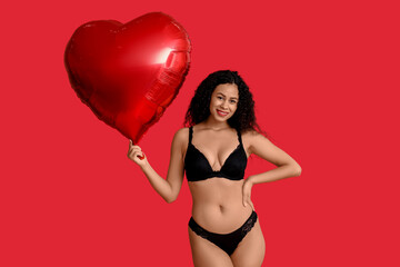 Beautiful young African-American woman in stylish black lingerie with air balloon in shape of heart...