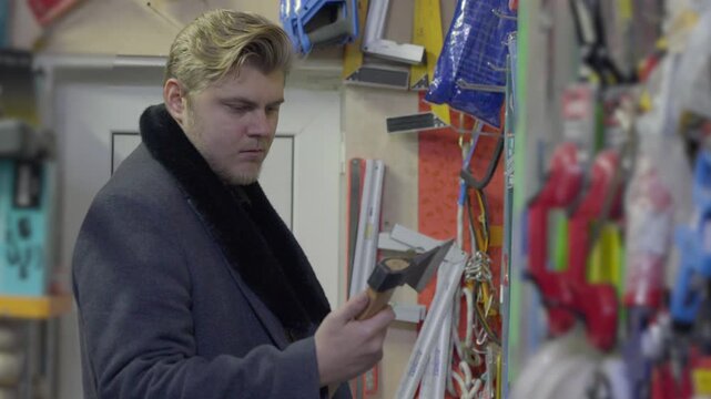 Man in a coat looking at tools in hardware store