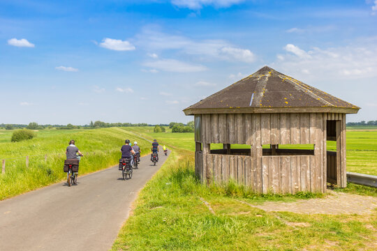Cyclists passing a bird watching hut at the dike near Papenburg, Germany