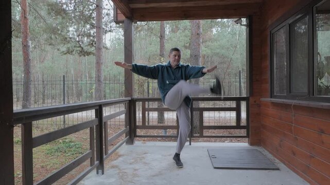 Man practicing balance exercise outdoors on wooden porch, Body coordination training demonstrating stability control and physical fitness