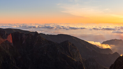 Sunrise over cloud sea and dramatic mountain ridge at Pico do Arieiro Madeira Portugal, golden dawn light lifts rugged peaks above glowing clouds near the Atlantic horizon © Artem