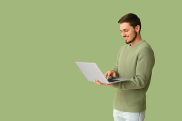Handsome young man using laptop on green background. Online dating concept
