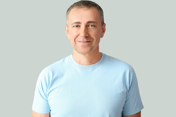Fototapeta premium Portrait of smiling mature man on grey background
