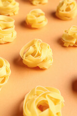 Composition with uncooked tagliatelle pasta on beige background, closeup