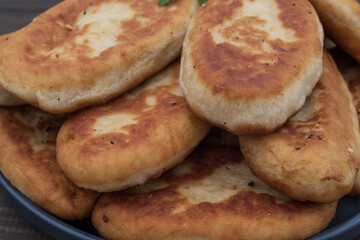 Golden fried potato pies arranged on a plate with fresh parsley. Classic homemade comfort food photographed on rustic wooden background for culinary use.
